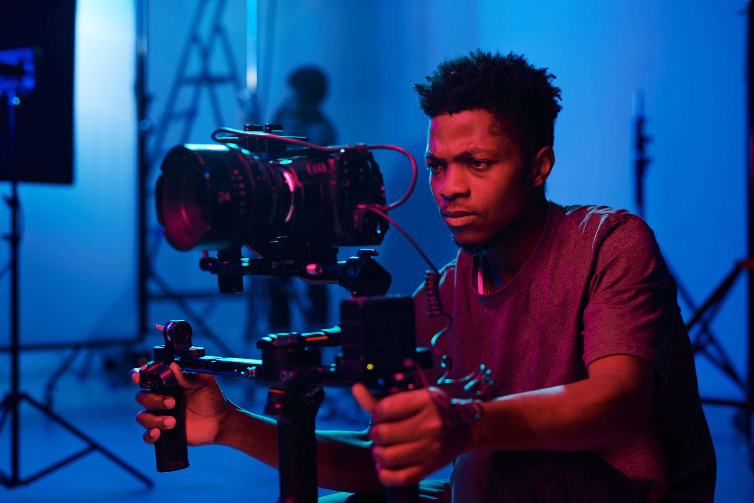 A young man holding a camera in a studio.