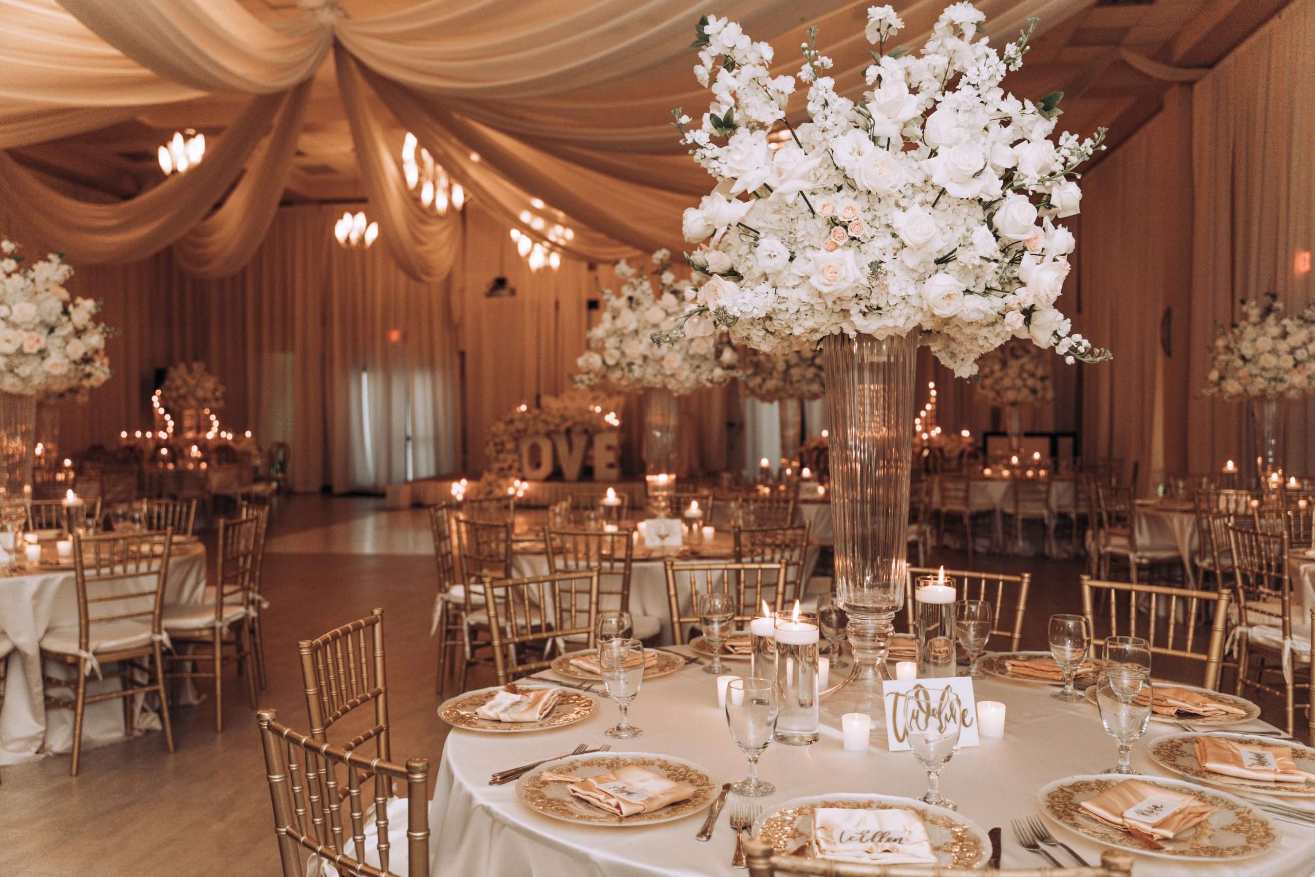 A white and gold wedding reception with candles and flowers.