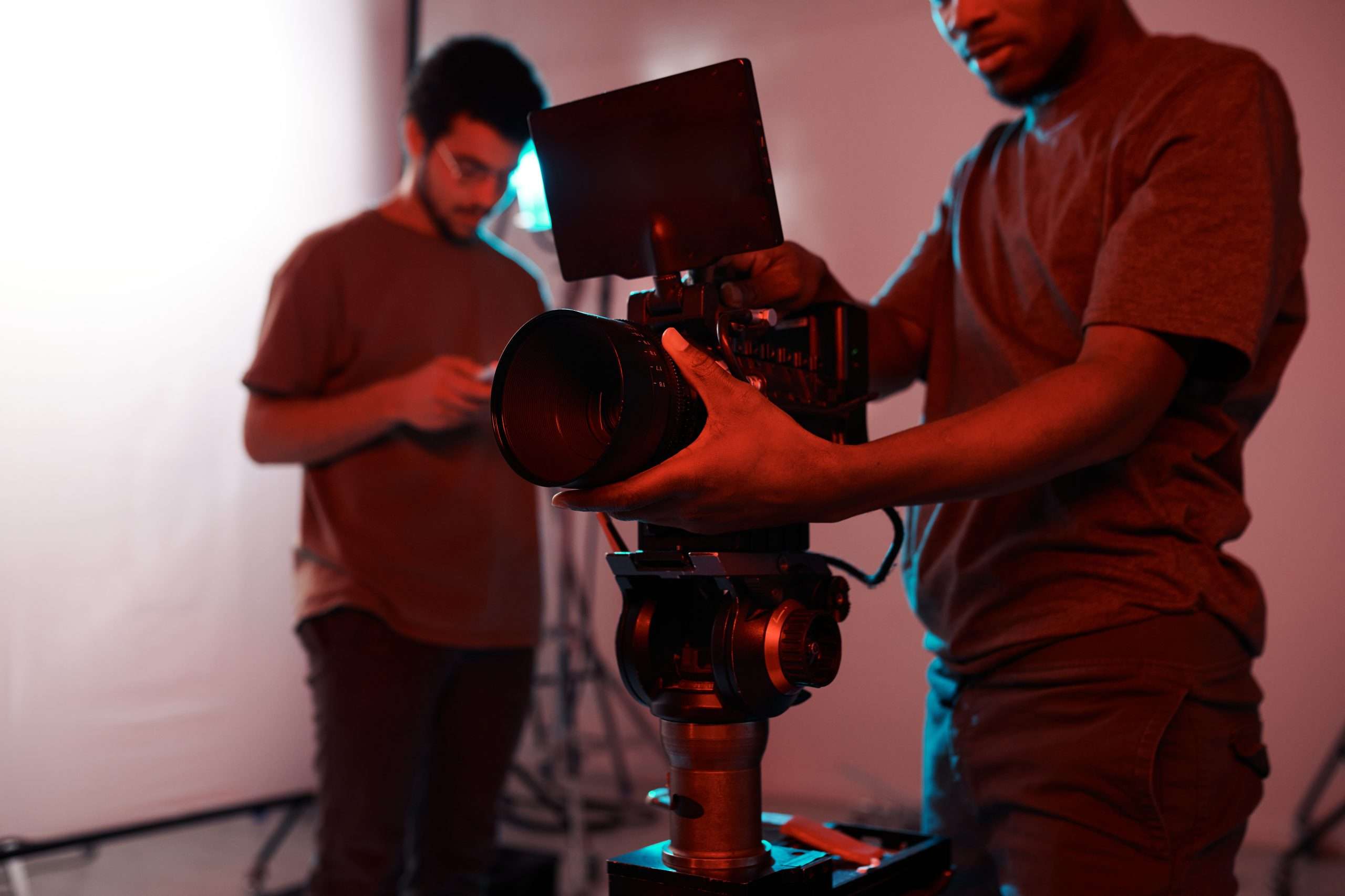 Two men working on a video camera in a studio.